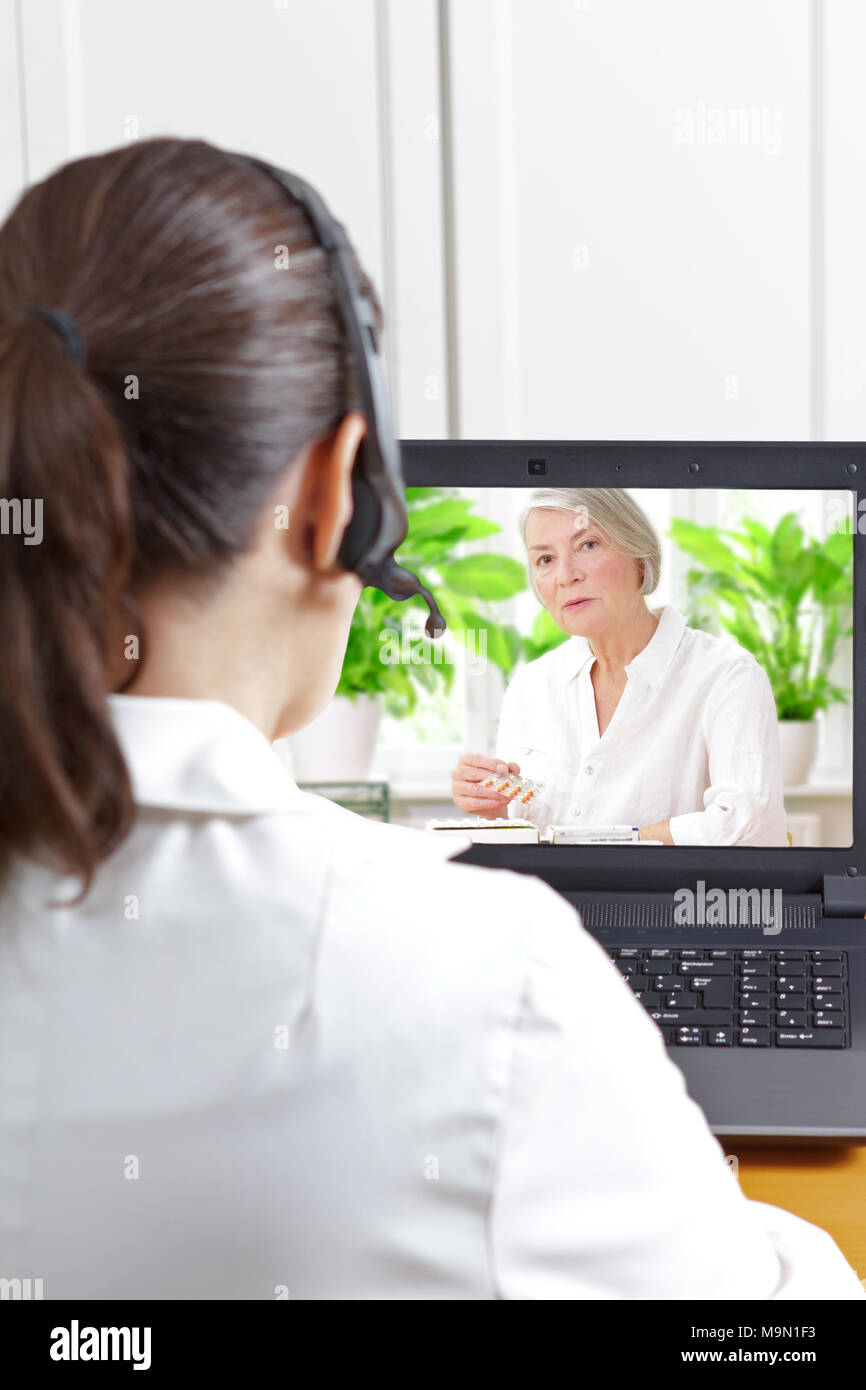 Femme médecin de la gériatrie avec casque en face de son ordinateur portable pendant un appel vidéo avec une vieille patiente sur son médicaments prescrits, la santé numérique Banque D'Images
