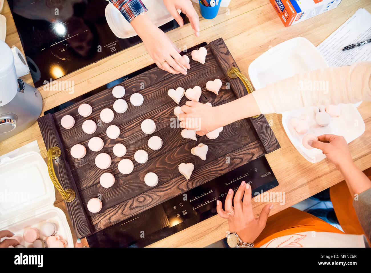 Haut de la main de femme vue mettre les cookies français macrons sur balances de cuisine Banque D'Images