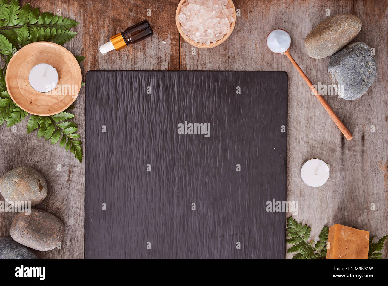 Les échantillons de produits de beauté et de sels de bain avec feuilles et pierre noire sur table en bois Banque D'Images