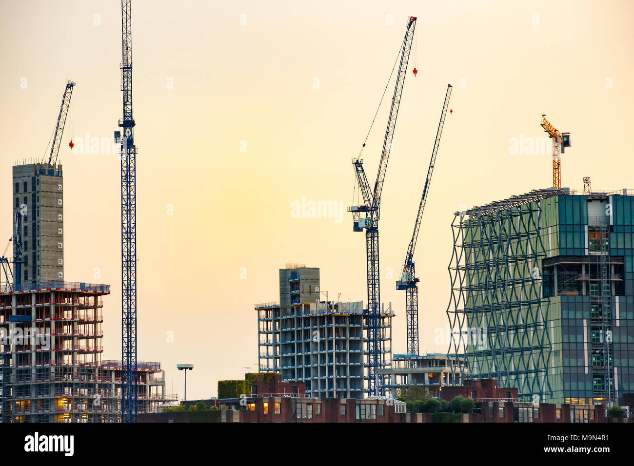 De nouveaux gratte-ciel en construction avec de grandes grues contre ciel coloré. Entreprise de construction et de l'industrie, l'urbanisation, l'étalement urbain real estate Banque D'Images