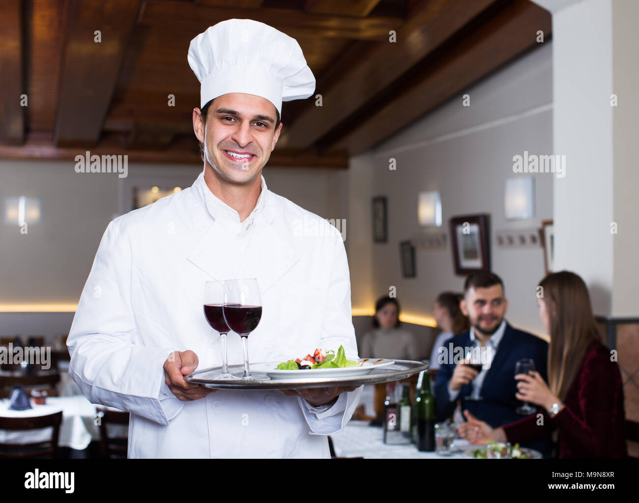 Portrait of handsome male chef avec plateau de service accueillant pour restaurant Banque D'Images