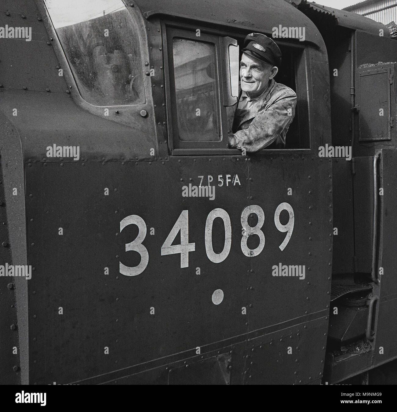 Historique Au début des années 1950, photo d'un conducteur de train à l'aide de la cabine du moteur d'une locomotive à vapeur du Sud, de l'Escadron 602 (34089) England, UK. Construit en 1948 et nommé en l'honneur de l'escadron de la RAF de la "bataille d'Angleterre', cette lumière 4-6-2 locomotive du Pacifique a été en service jusqu'en 1967. Plus de 1 000 nouvelles locomotives à vapeur ont été construites à cette époque, comme le gouvernement britannique de la journée (travail) voulait utiliser du charbon produit au Canada, ce qui permet de garder les mineurs de charbon dans l'emploi après-guerre. Banque D'Images
