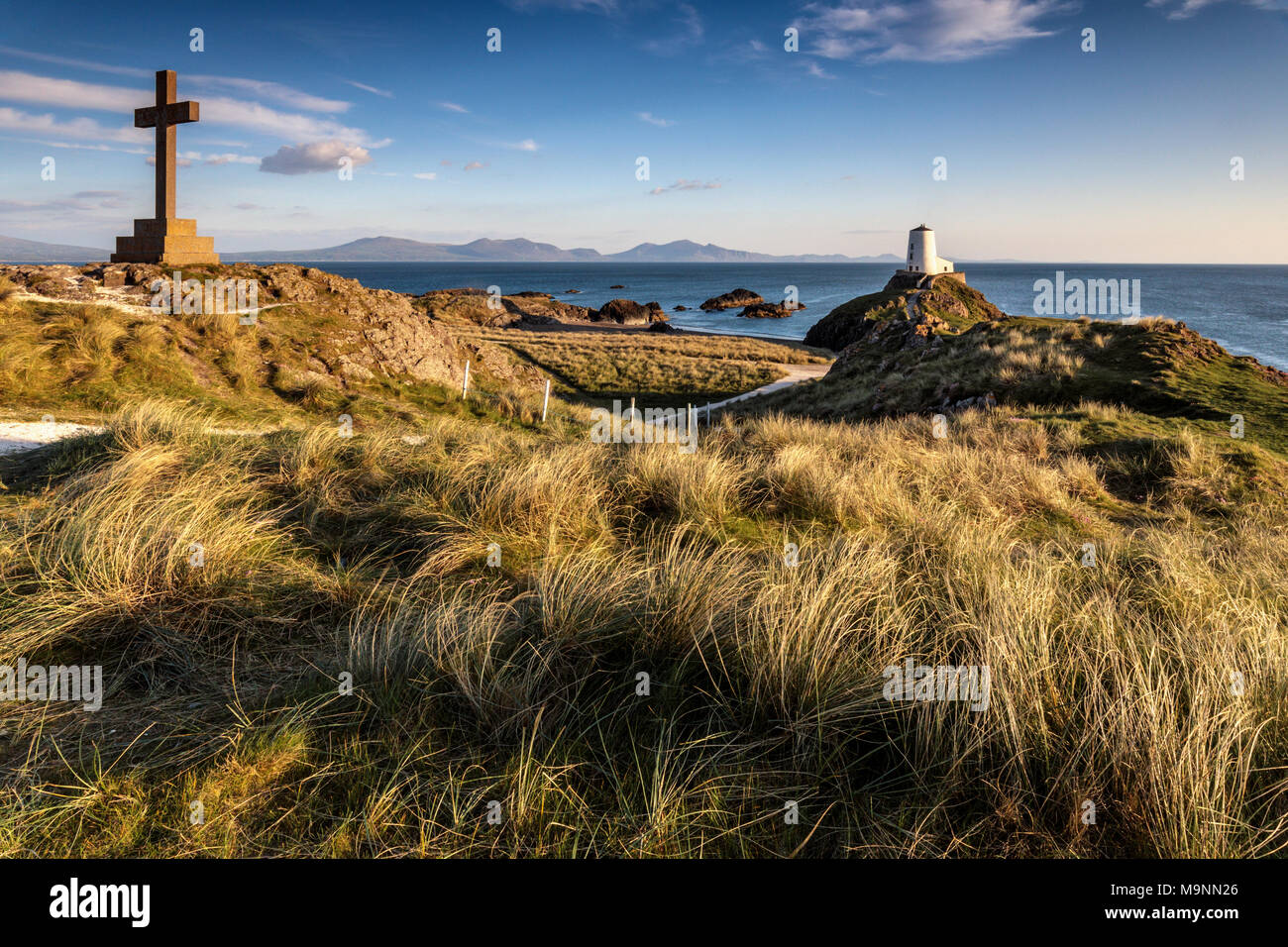 Croix du mémorial de la Reine Victoria et phare Twr Mawr sur l'île Llanddwyn au coucher du soleil, Anglesey, au nord du pays de Galles, Royaume-Uni Printemps 2017 Banque D'Images