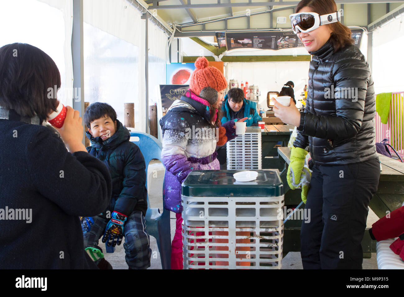 Une asiatique à la famille est l'échauffement à l'intérieur d'une tente, à côté d'un radiateur, avec du chocolat chaud. Yongpyong (Dragon Valley) Ski Resort est une station de ski en Corée du Sud, situé dans la région de Daegwallyeong-myeon, Pyeongchang, Gangwon-do. C'est la plus grande station de ski et snowboard en Corée. Technique de Yongpyong accueillera les épreuves de ski alpin pour les Jeux olympiques et paralympiques d'hiver de 2018 à Pyeongchang. Certaines scènes de la Korean Broadcasting System 2002 drama Winter Sonata ont été tournées dans la station. Banque D'Images