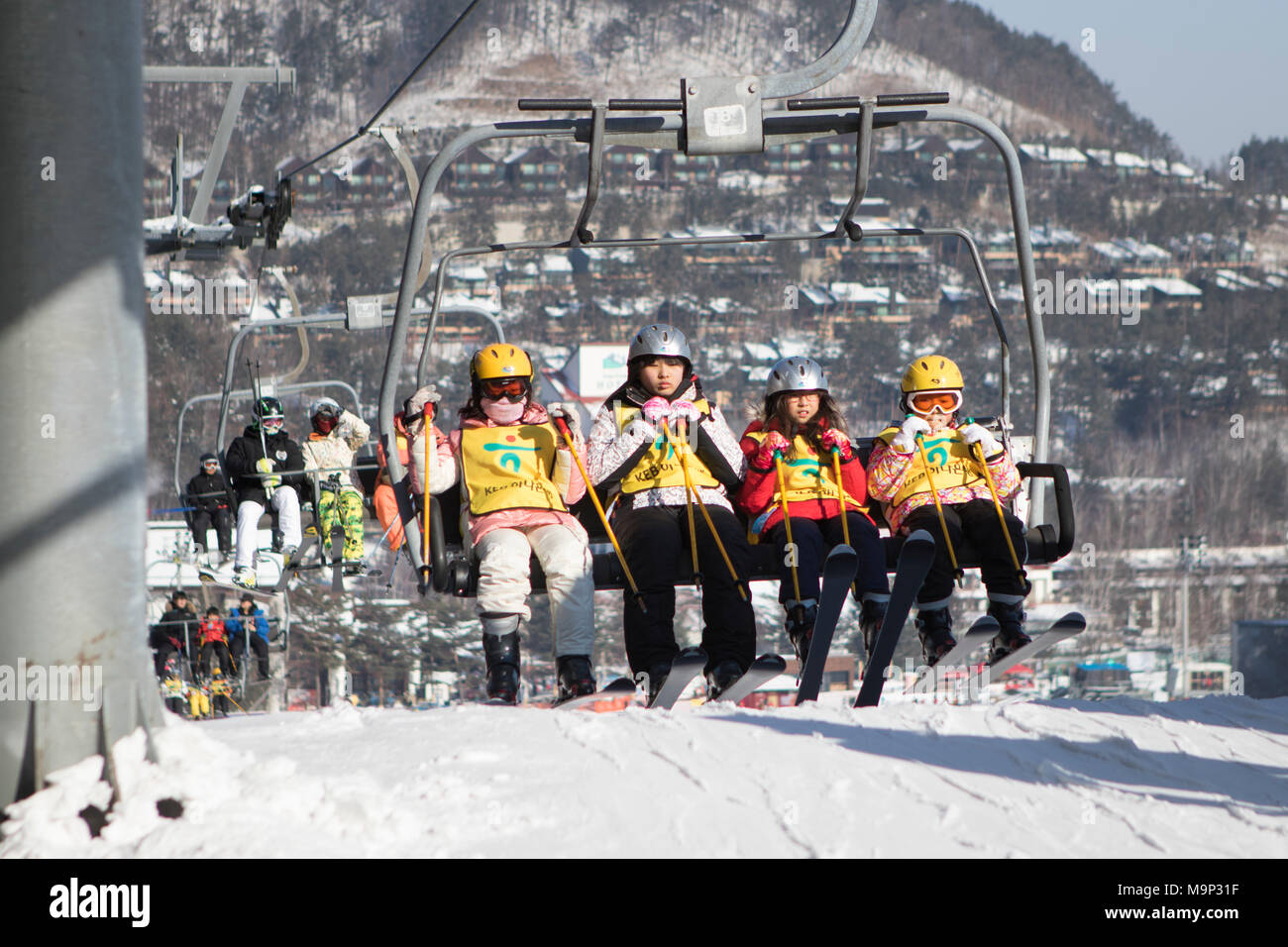 Un groupe de quatre enfants est d'arriver à la station supérieure du télésiège du bunny pente à Yongpyong. Yongpyong (Dragon Valley) Ski Resort est une station de ski en Corée du Sud, situé dans la région de Daegwallyeong-myeon, Pyeongchang, Gangwon-do. C'est la plus grande station de ski et snowboard en Corée. Technique de Yongpyong accueillera les épreuves de ski alpin pour les Jeux olympiques et paralympiques d'hiver de 2018 à Pyeongchang. Certaines scènes de la Korean Broadcasting System 2002 drama Winter Sonata ont été tournées dans la station. Banque D'Images