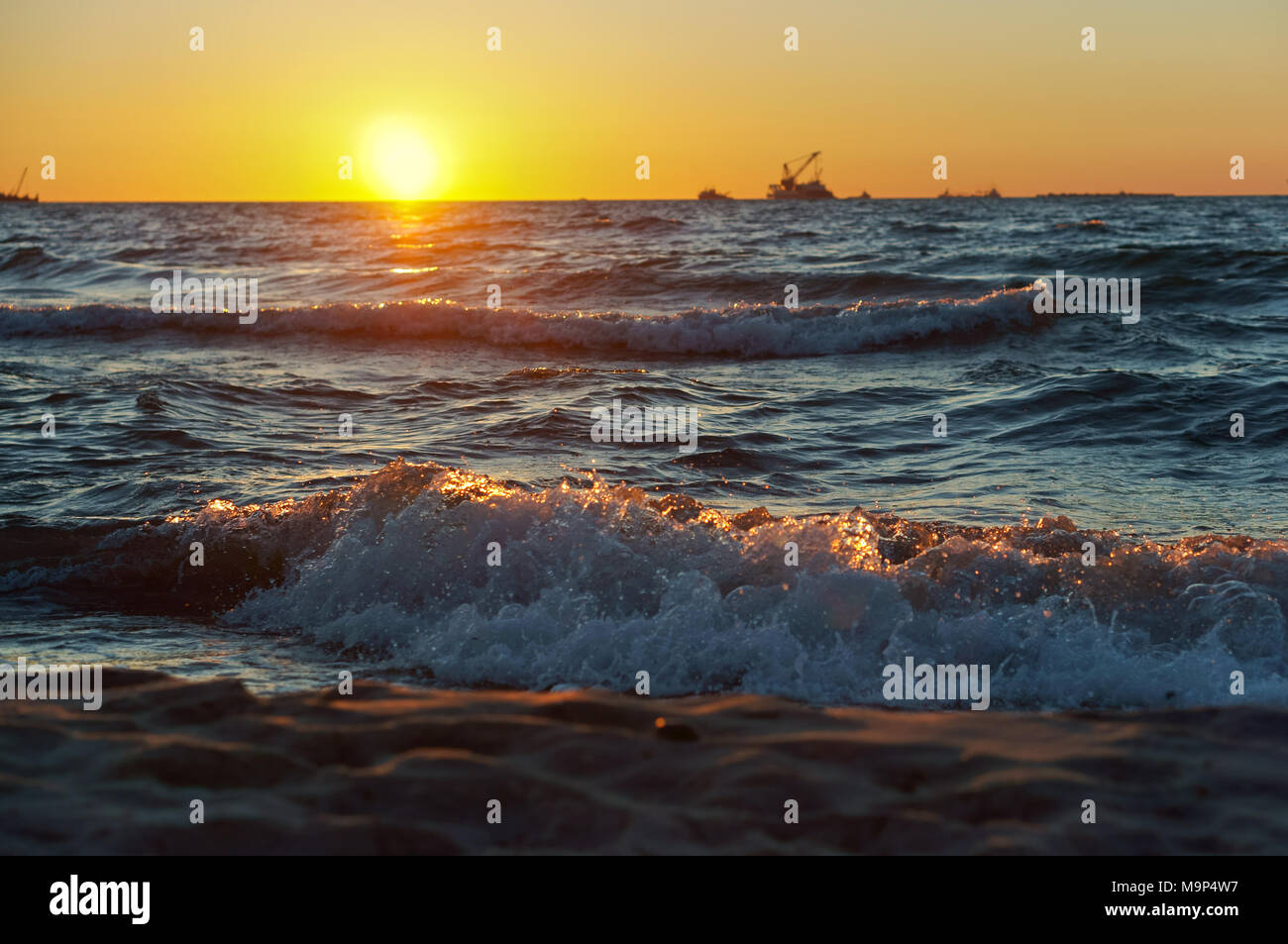 Coucher de soleil sur la mer. Reflet de la lumière du soleil dans les vagues de la mer. Ciel rouge dans les rayons du coucher du soleil. Banque D'Images