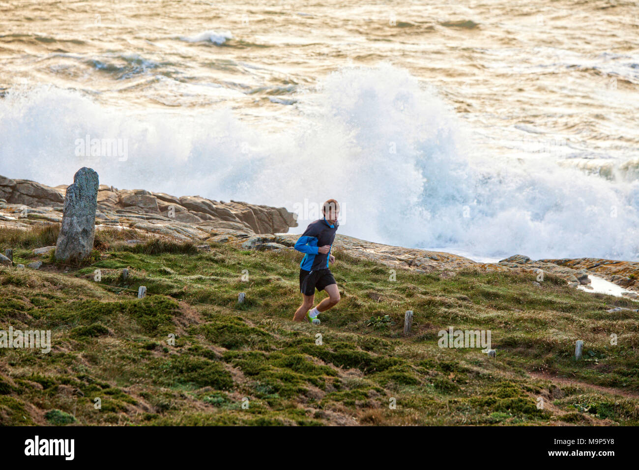 Homme qui court pendant une tempête sur les côtes, Kerroch, Bretagne, France Banque D'Images