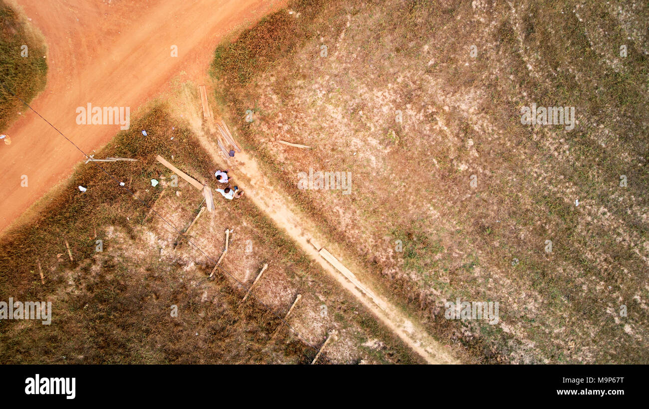 Eagle View L'œil de l'oiseau à partir d'un drone d'un franchissement routier de couleur rouge des champs de riz au Cambodge Banque D'Images