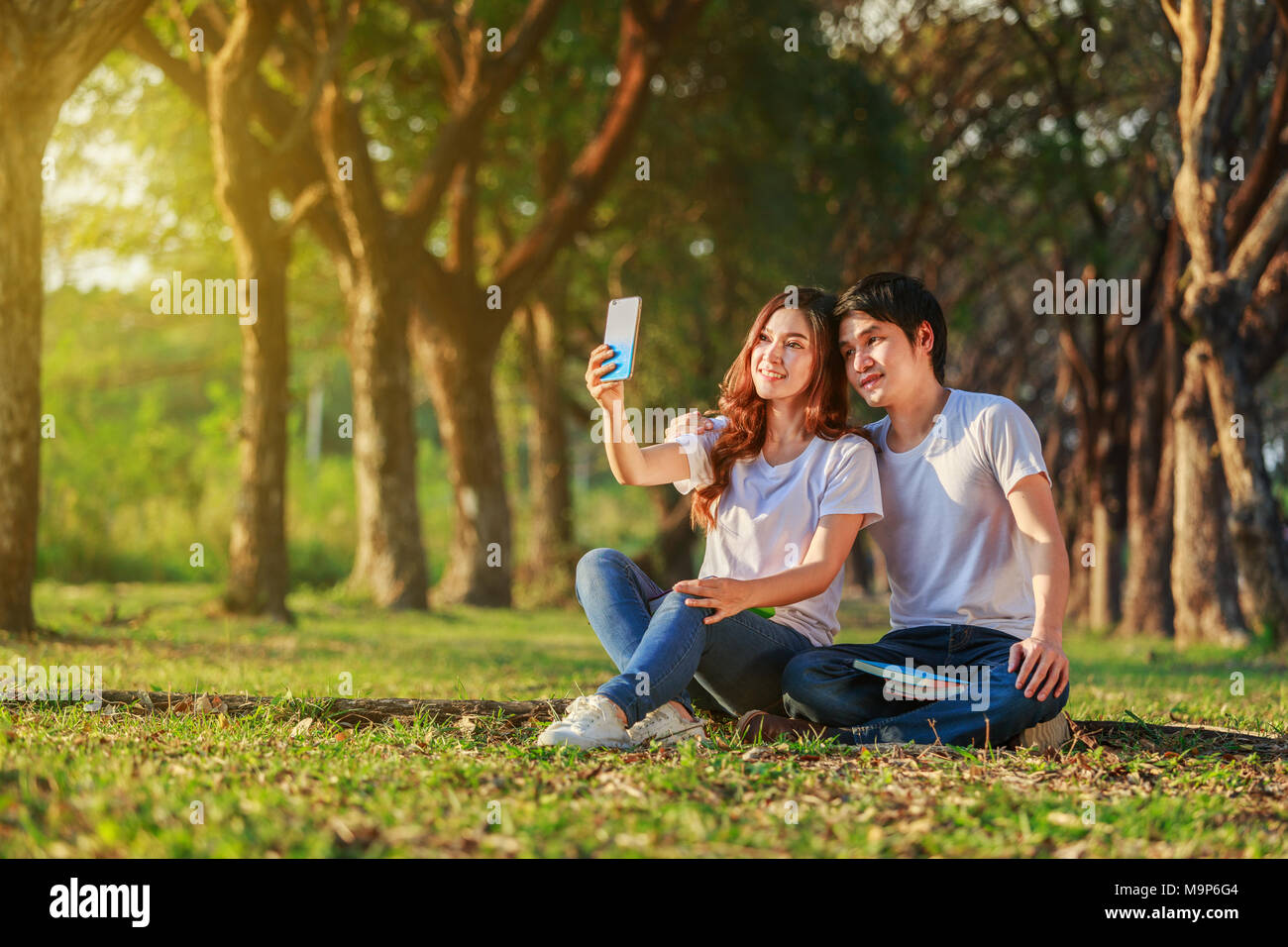 Jeune couple à l'aide d'un téléphone mobile dans le parc selfies Banque D'Images