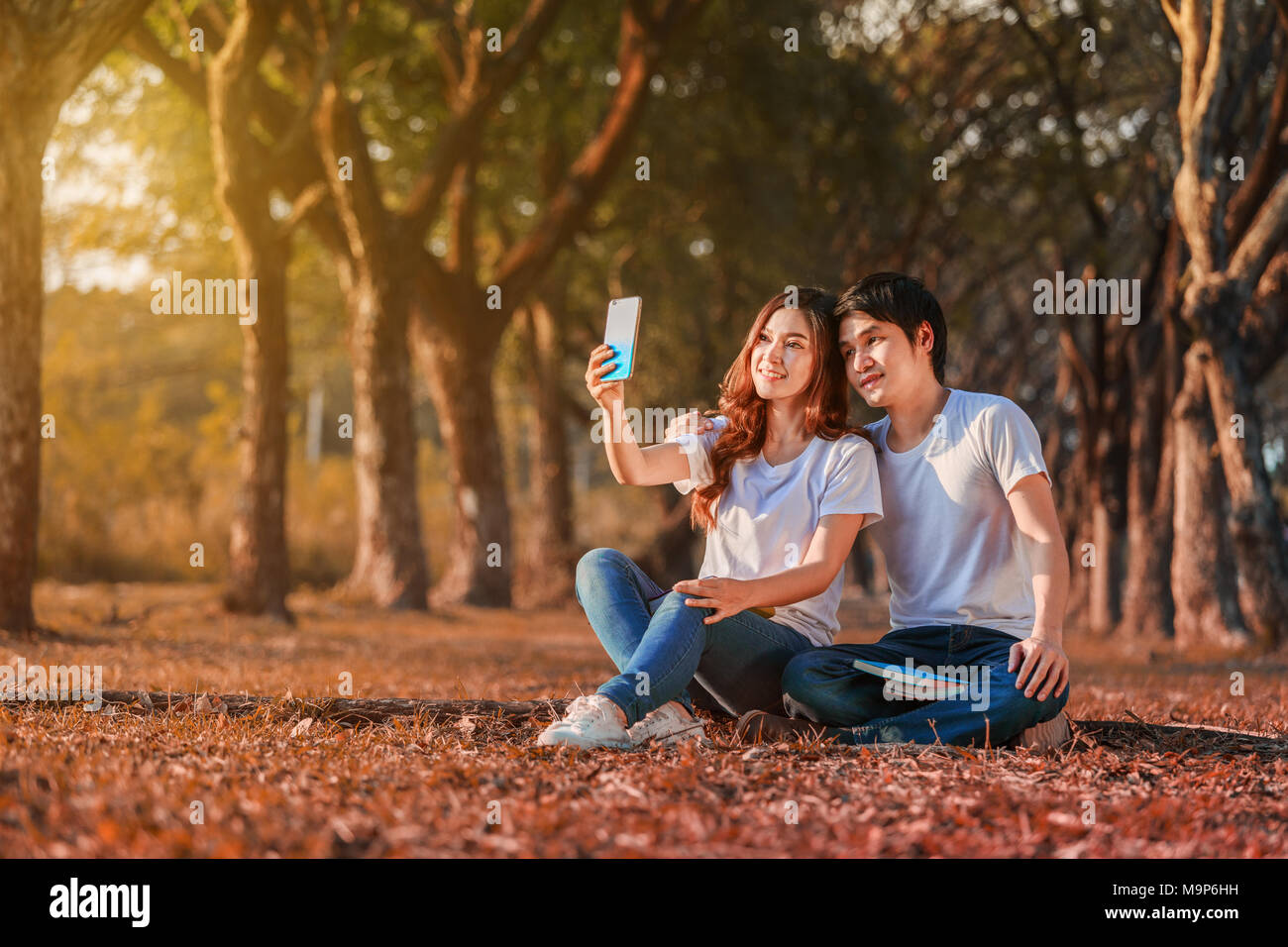 Jeune couple à l'aide d'un téléphone mobile dans le parc selfies Banque D'Images