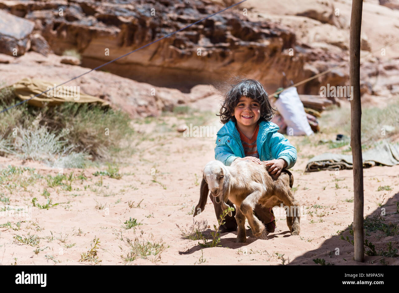 Jeune fille jouant avec des Bédouins dans la chèvre bébé Wadi Rum désert près de la frontière de l'Arabie Saoudite. Banque D'Images