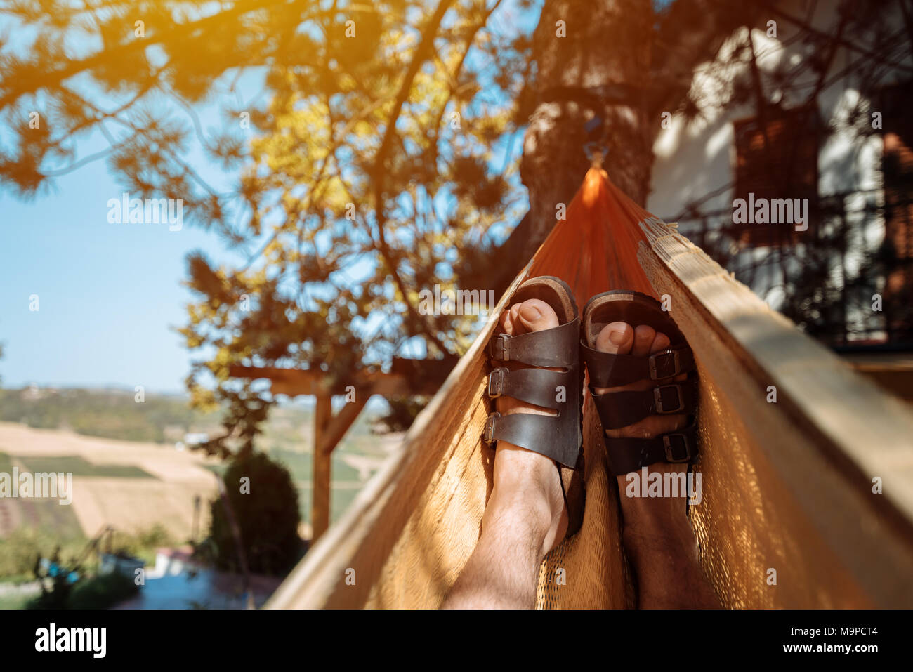 Pose de l'homme et de vous détendre dans un hamac, Close up of male détendue pieds se balançant dans le hamac dans matin d'été Banque D'Images