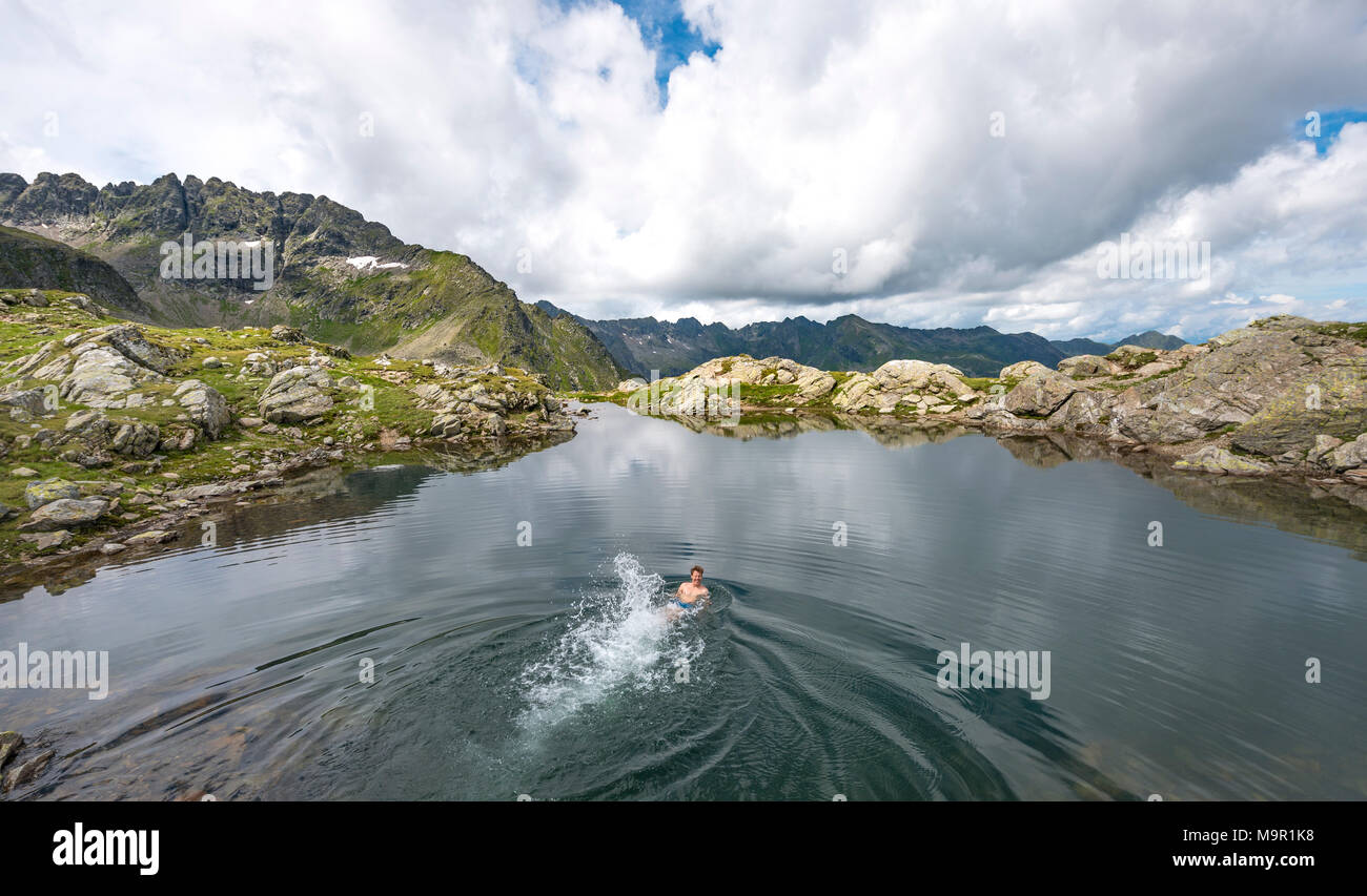 Jeune homme nageant dans un petit lac, Klafferkessel, Schladminger Tauern Schladminger, Höhenweg, Schladming, Styrie, Autriche Banque D'Images