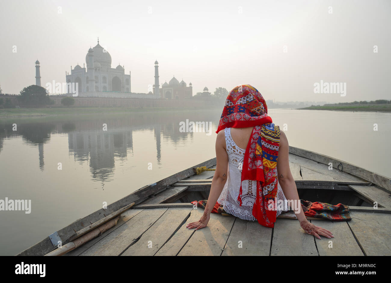 Une femme asiatique regardant le coucher du soleil sur le Taj Mahal à partir d'un bateau en bois. Banque D'Images