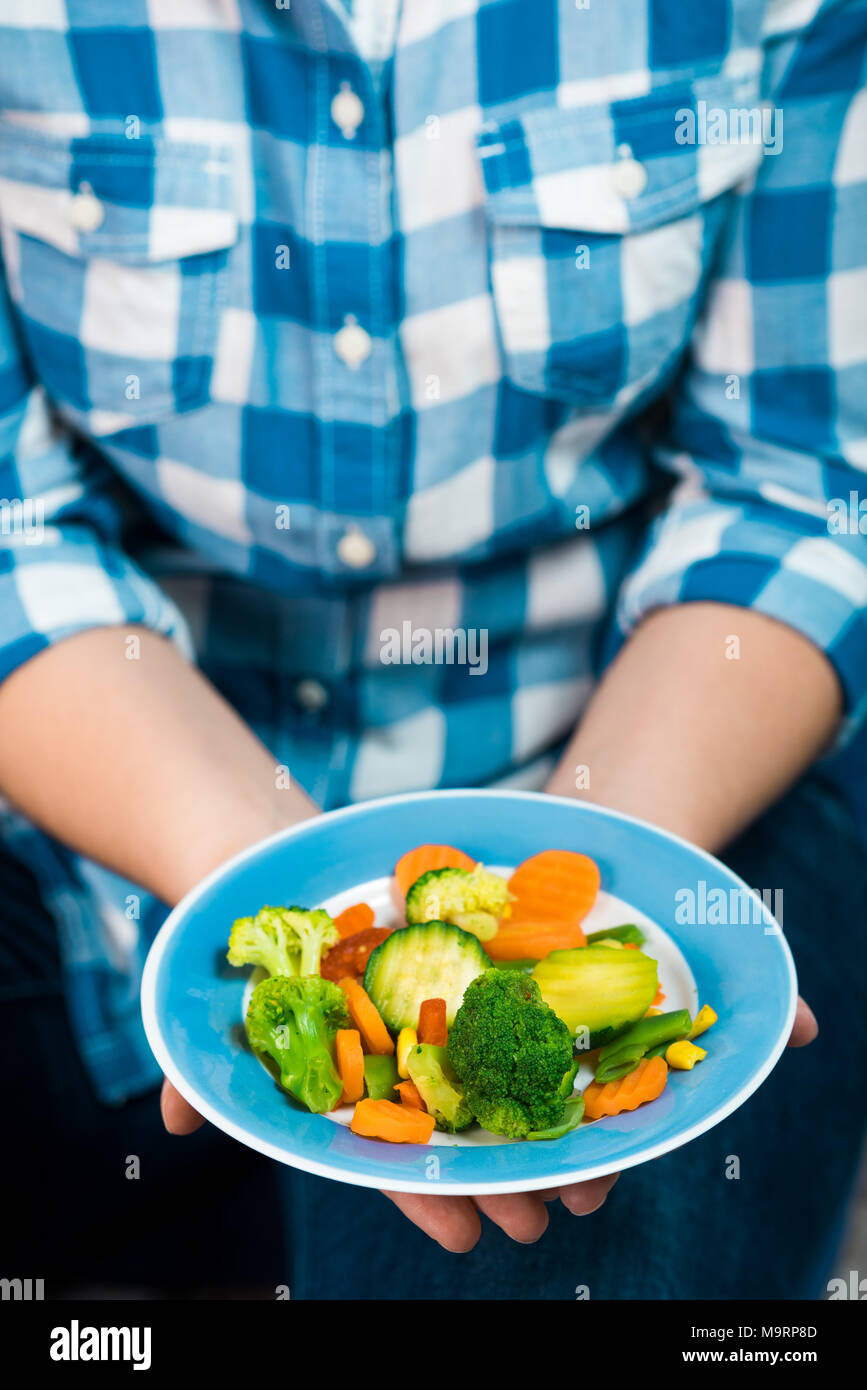 Fille avec une assiette de légumes en mains Banque D'Images