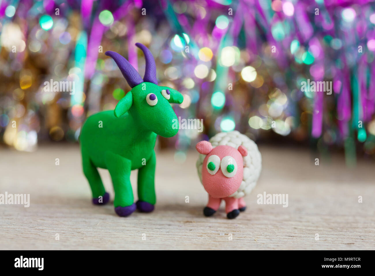 Monde - Pâte à modeler maison petit chèvre vert violet avec des cornes et des sabots et les moutons se dresse sur un plancher en bois, selective focus et la place pour le texte Banque D'Images