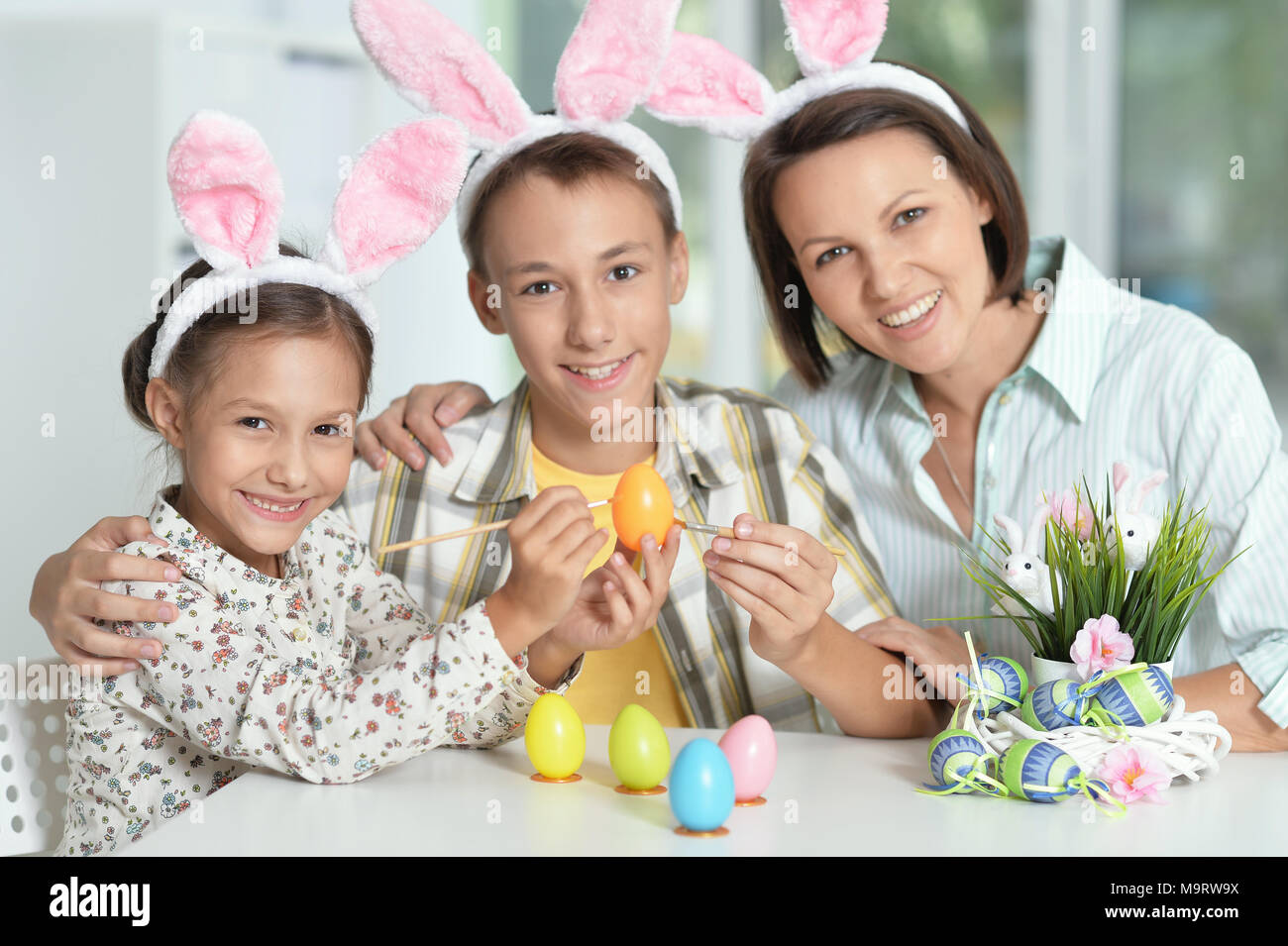 Mère avec son fils et sa fille portant des oreilles de lapin de Pâques oeufs peinture Banque D'Images