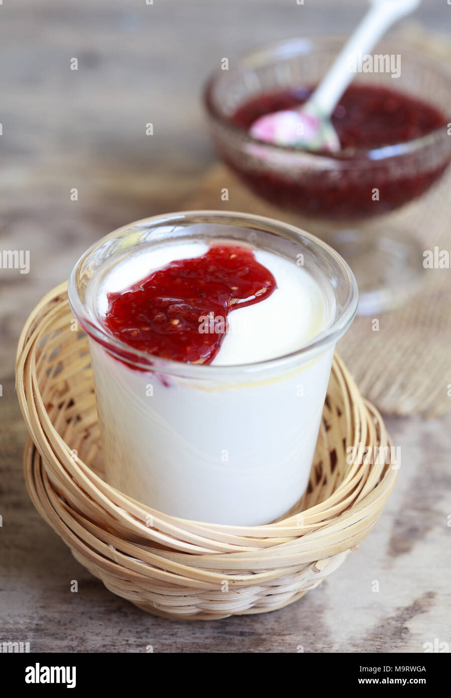 Petit pot de yaourts à la confiture de framboises dans un des paniers d'osier sur une table en bois, selective focus Banque D'Images
