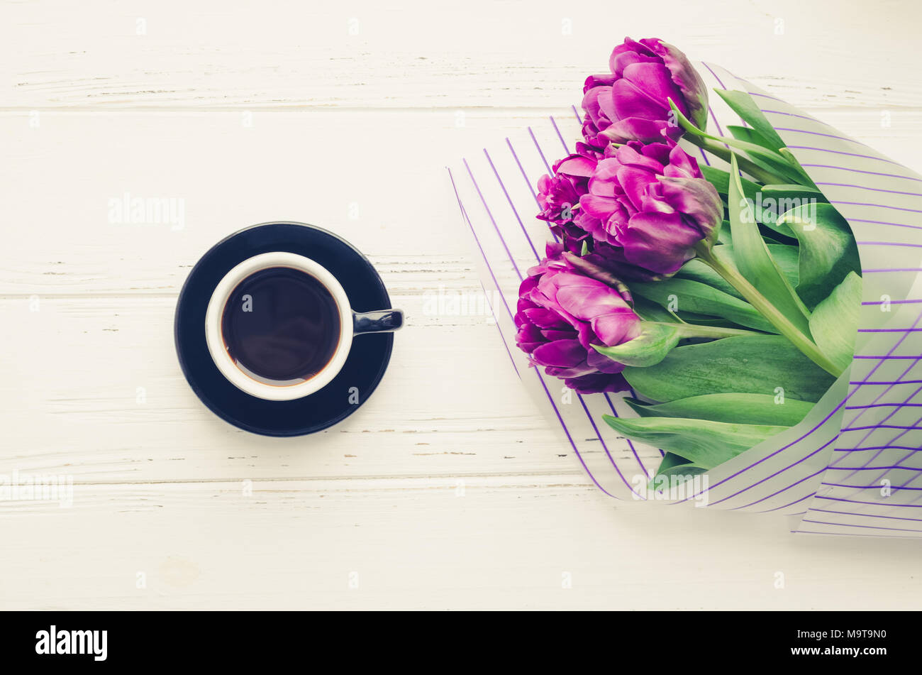 Tasse de café du matin et le bouquet de fleurs de printemps tulipes blanches sur fond de bois. Vue d'en haut. Matin carte de vœux. Maison de vacances romantique, moderne de l Banque D'Images