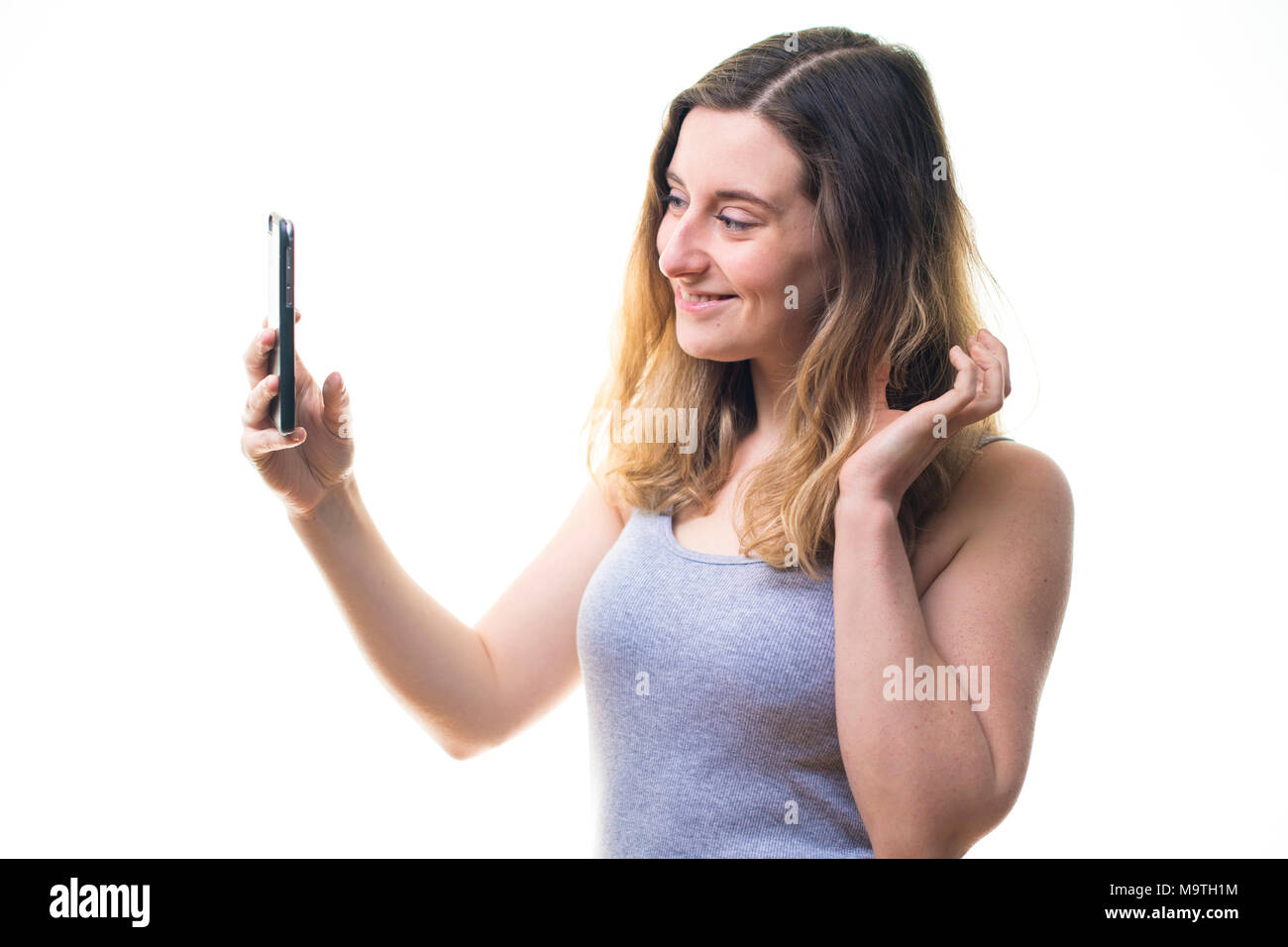 Une jeune femme de race blanche girl making a l'aide d'une photographie selfies iPhone téléphone cellulaire téléphone mobile , d'afficher sur son instagram snapchat et autres médias sociaux - UK Banque D'Images