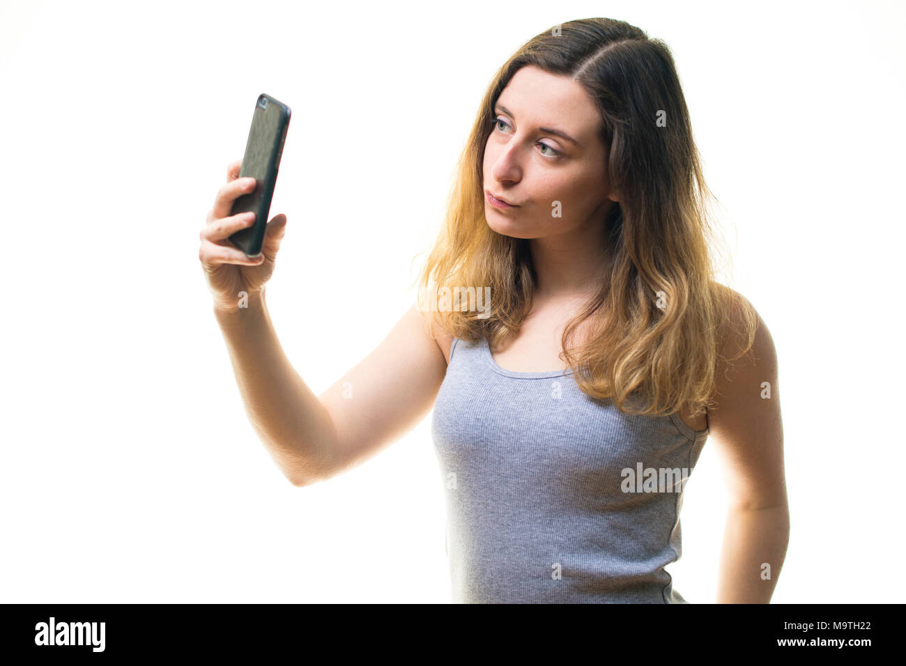 Une jeune femme de race blanche girl making a l'aide d'une photographie selfies iPhone téléphone cellulaire téléphone mobile , d'afficher sur son instagram snapchat et autres médias sociaux - UK Banque D'Images