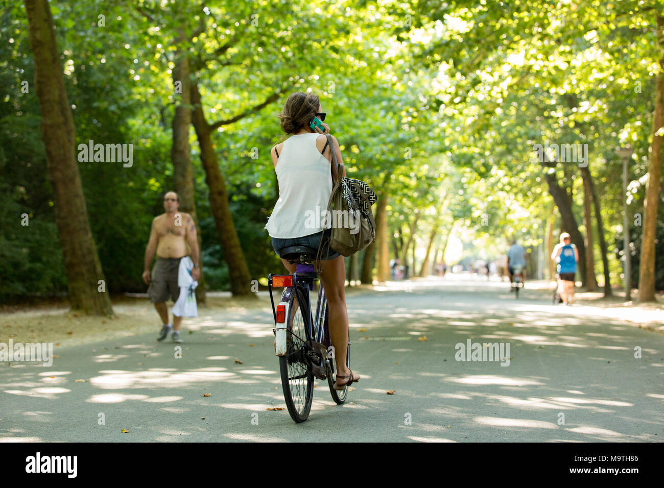Une fille cycliste et appelant dans le Vondelpark à Amsterdam aux Pays-Bas. Banque D'Images