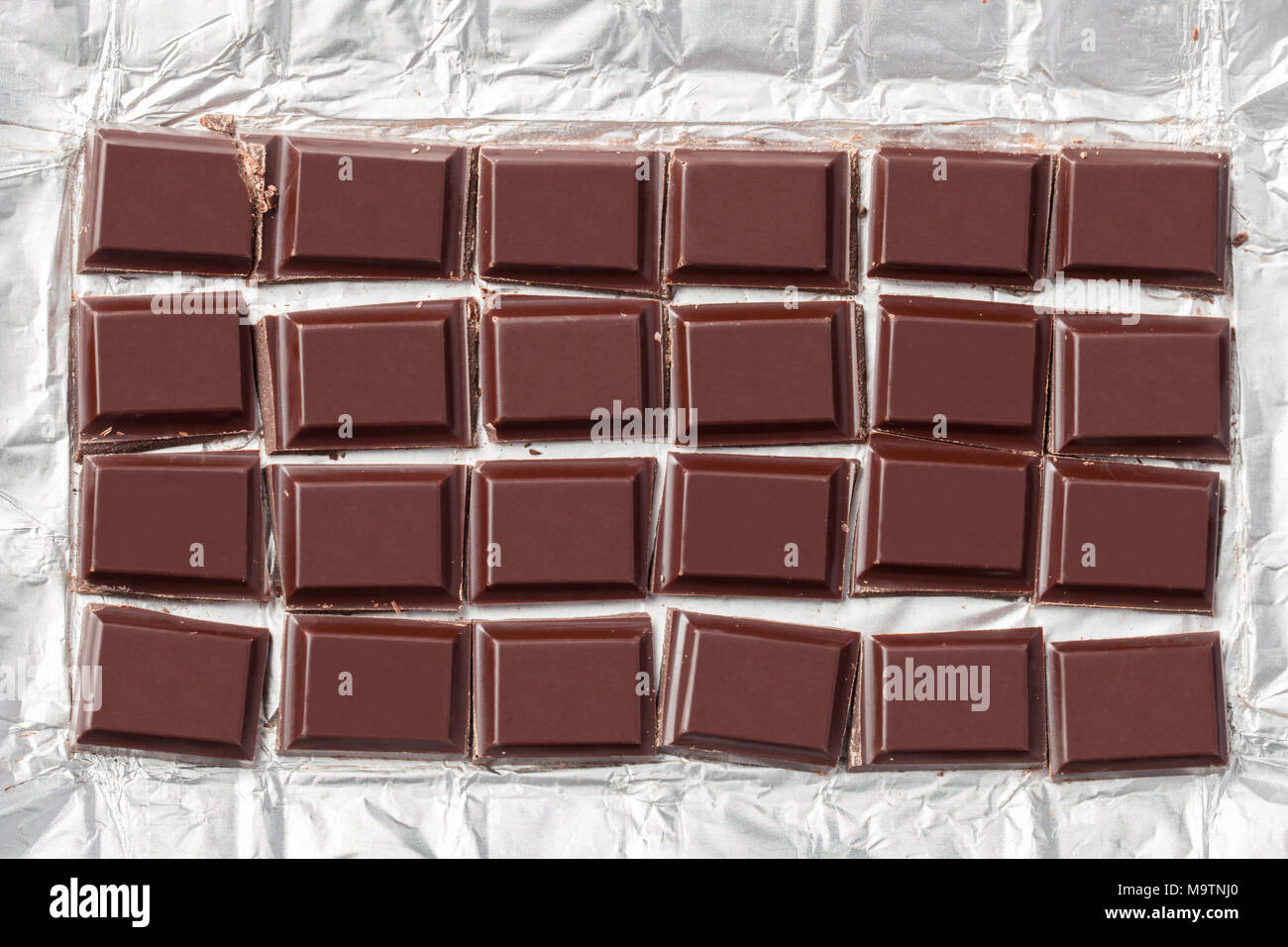 Broyée en morceaux d'une barre de chocolat noir dans le film métallique de l'emballage. Banque D'Images