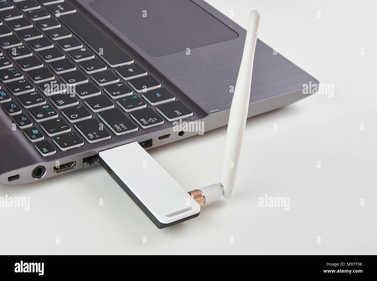 Ordinateur portable avec modem USB Argent branché avec une antenne, sur une table de carte blanche Banque D'Images