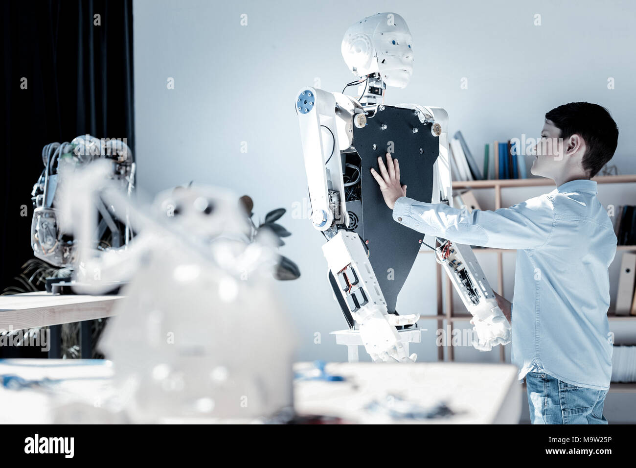 Surpris jeune poitrine touchant de machine robotique Banque D'Images