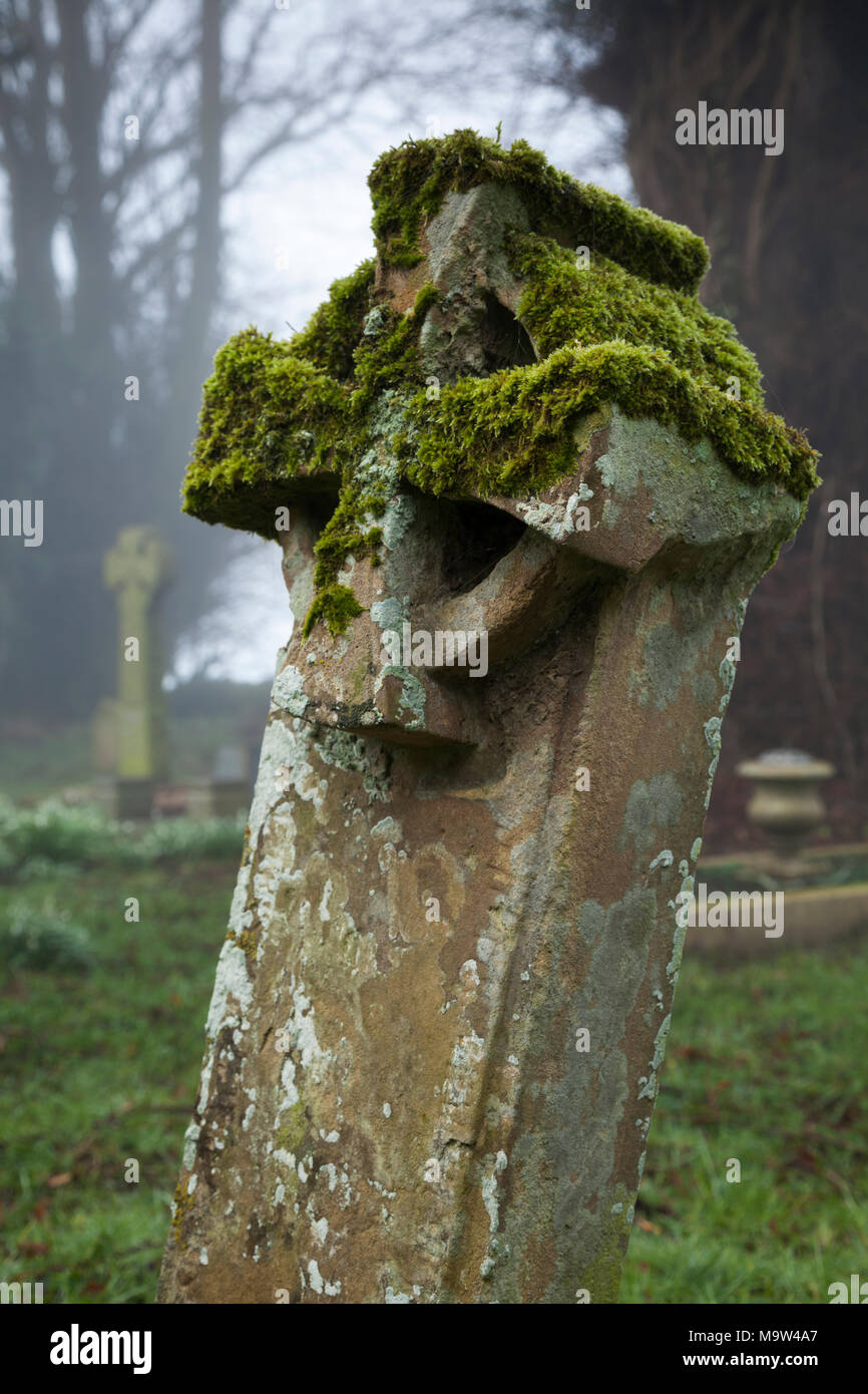 Un matin brumeux parmi les pierres tombales dans un cimetière, l'église All Saints, Holdenby, Northamptonshire, Angleterre. Banque D'Images