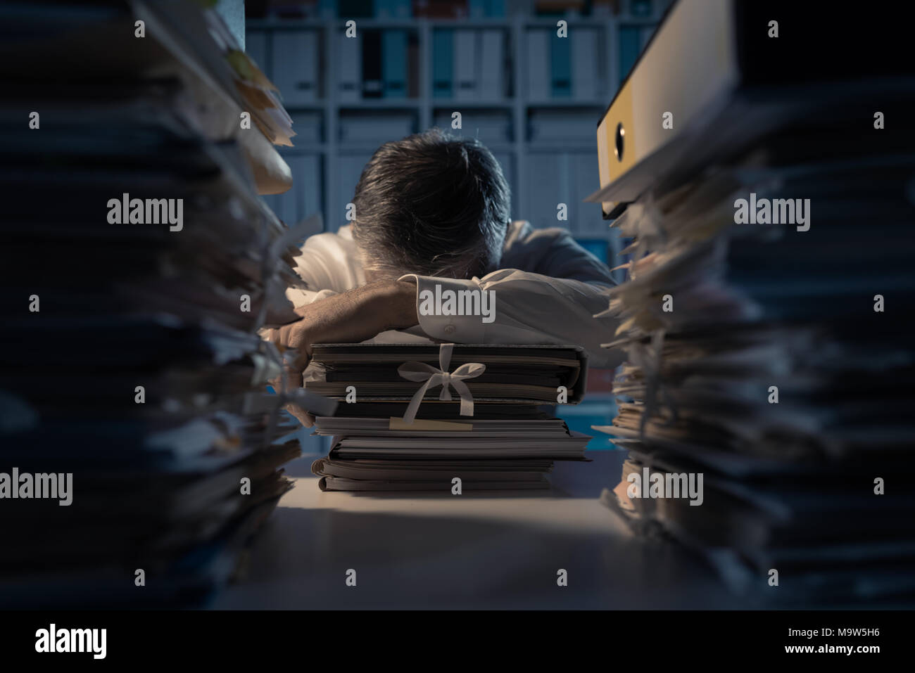 Office worker dormir sur le bureau tard dans la nuit, il est épuisé et  débordé de travail, son bureau est couvert de paperasse : délais et  manifeste Photo Stock - Alamy