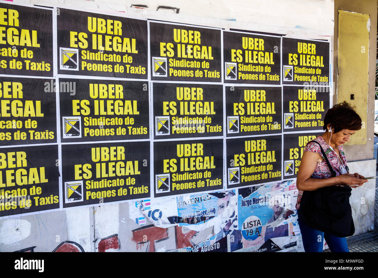 Buenos Aires Argentina,Recoleta,Avenida Las Heras,arrêt de bus,femme femmes,utilisant smartphone téléphone cellulaire, oreillettes, affiche de protestation, chauffeurs de taxi u Banque D'Images