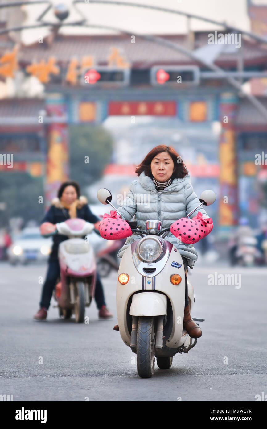 HENGDIAN-CHINE-déc. 29, 2014. Femme sur scooter électrique au design rétro. La Chine a 200 millions d'e-bikes fonctionnant sur la route, une multiplication par 10 à partir de 2005. Banque D'Images