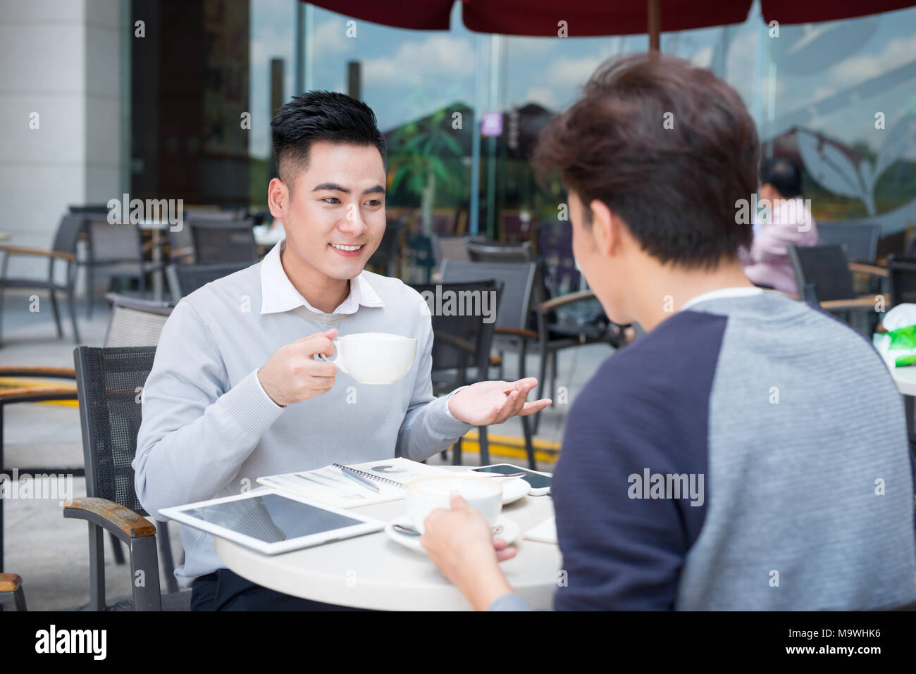 Deux jeunes hommes d'affaires dans les tenues de beau sourire, parler dans un café. Banque D'Images