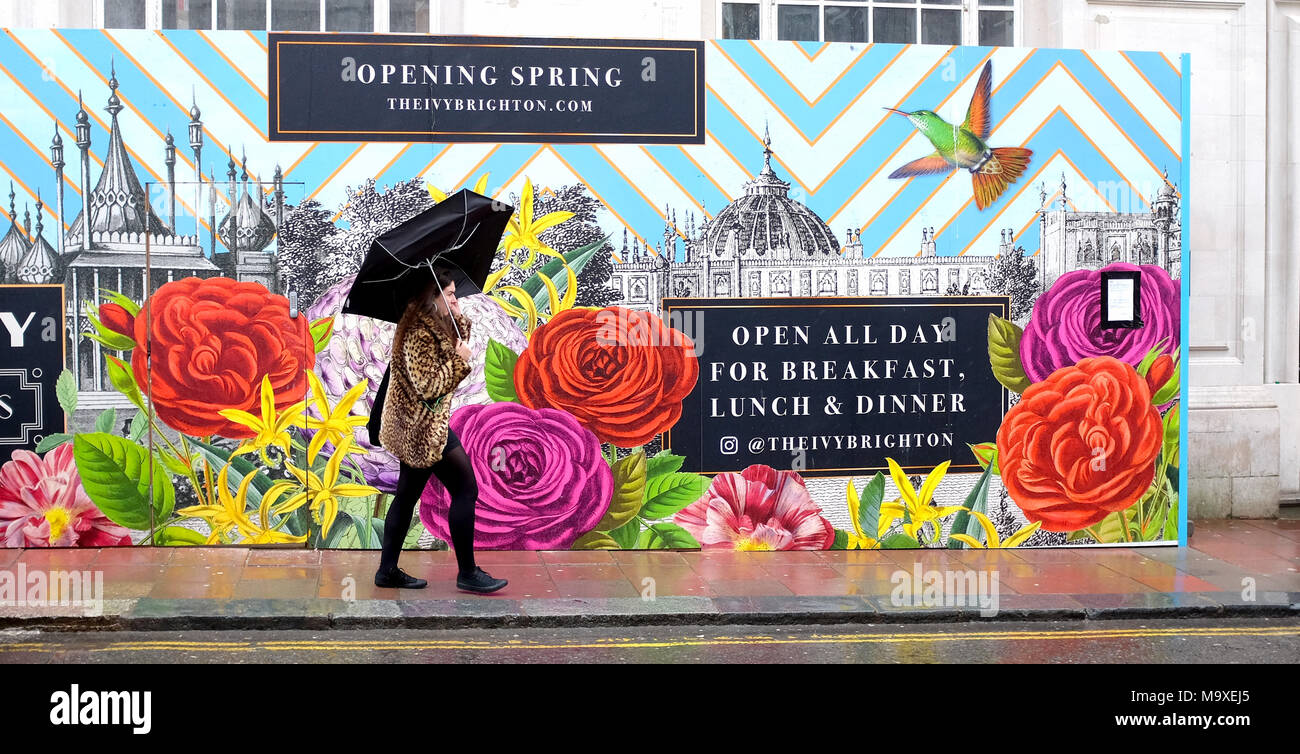 Crawley Royaume-uni 29 mars 2018 - une jeune femme se débat avec son parapluie sous la pluie alors qu'elle passe devant le nouveau restaurant de lierre sur une journée venteuse à Brighton aujourd'hui avec des prévisions de temps incertain pour le prochain week-end de Pâques : Crédit Simon Dack/Alamy Live News Banque D'Images