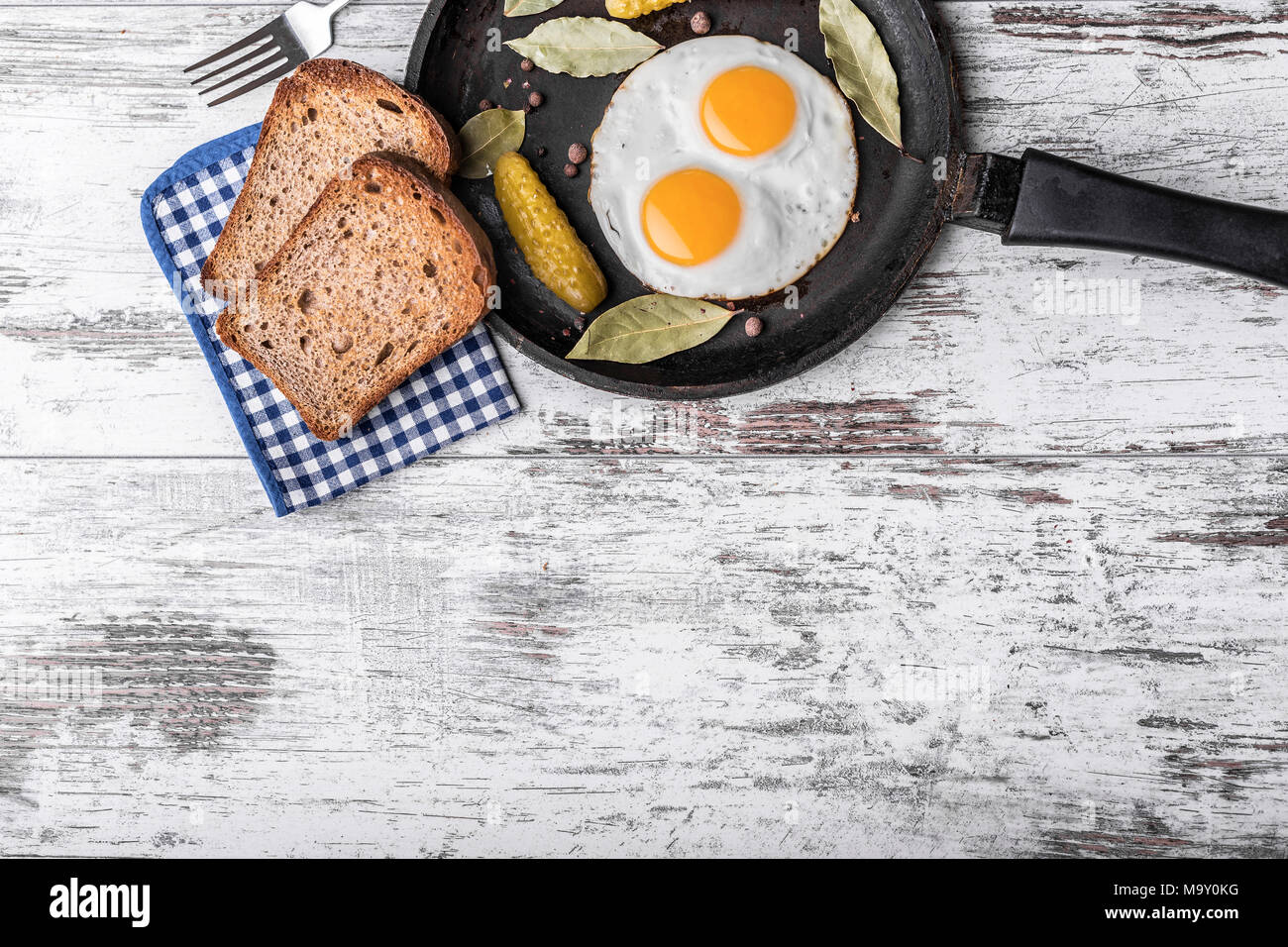 Oeufs frits à la poêle. Pain de seigle et cornichon à côté d'œufs au plat. Banque D'Images