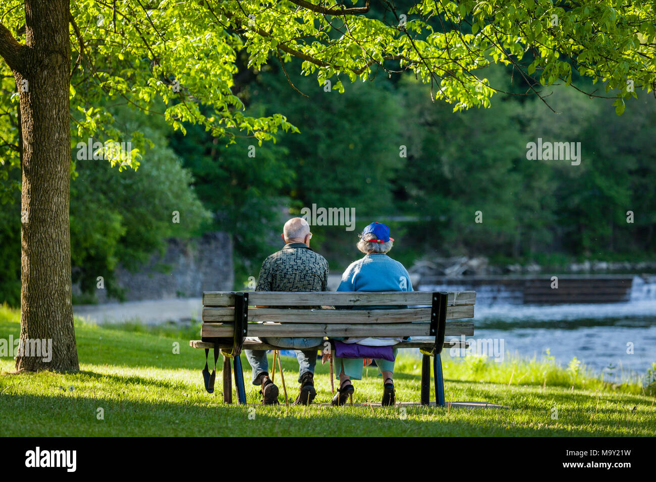 Couple assis sur un banc avec rivière et cascade en arrière-plan. Banque D'Images