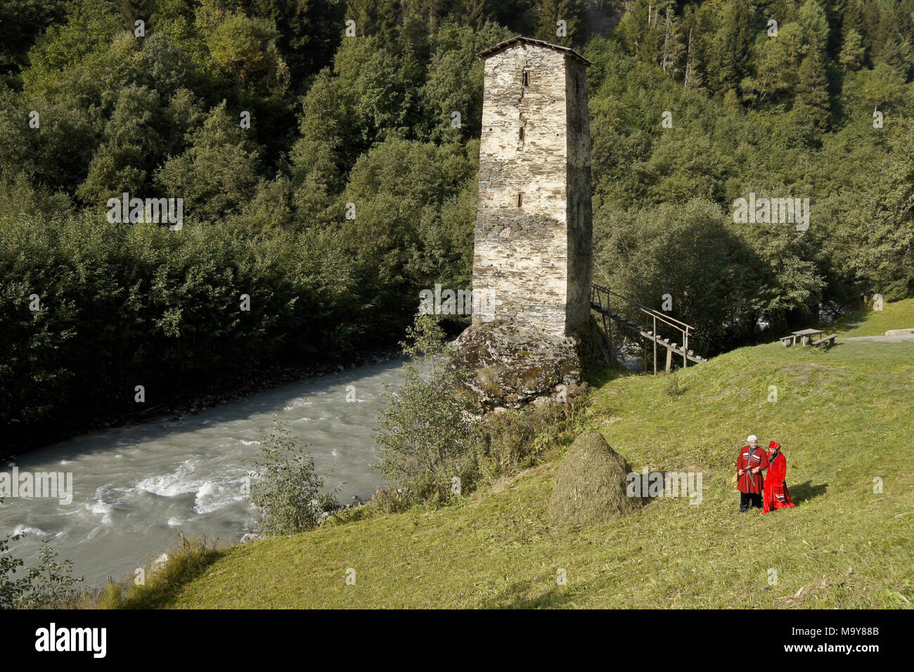 Un couple en costume national géorgien à pied près de l'Ingouri (Rivière Enguri) et la légendaire Tour de l'amour à Kala, Upper Svaneti, Géorgie Banque D'Images