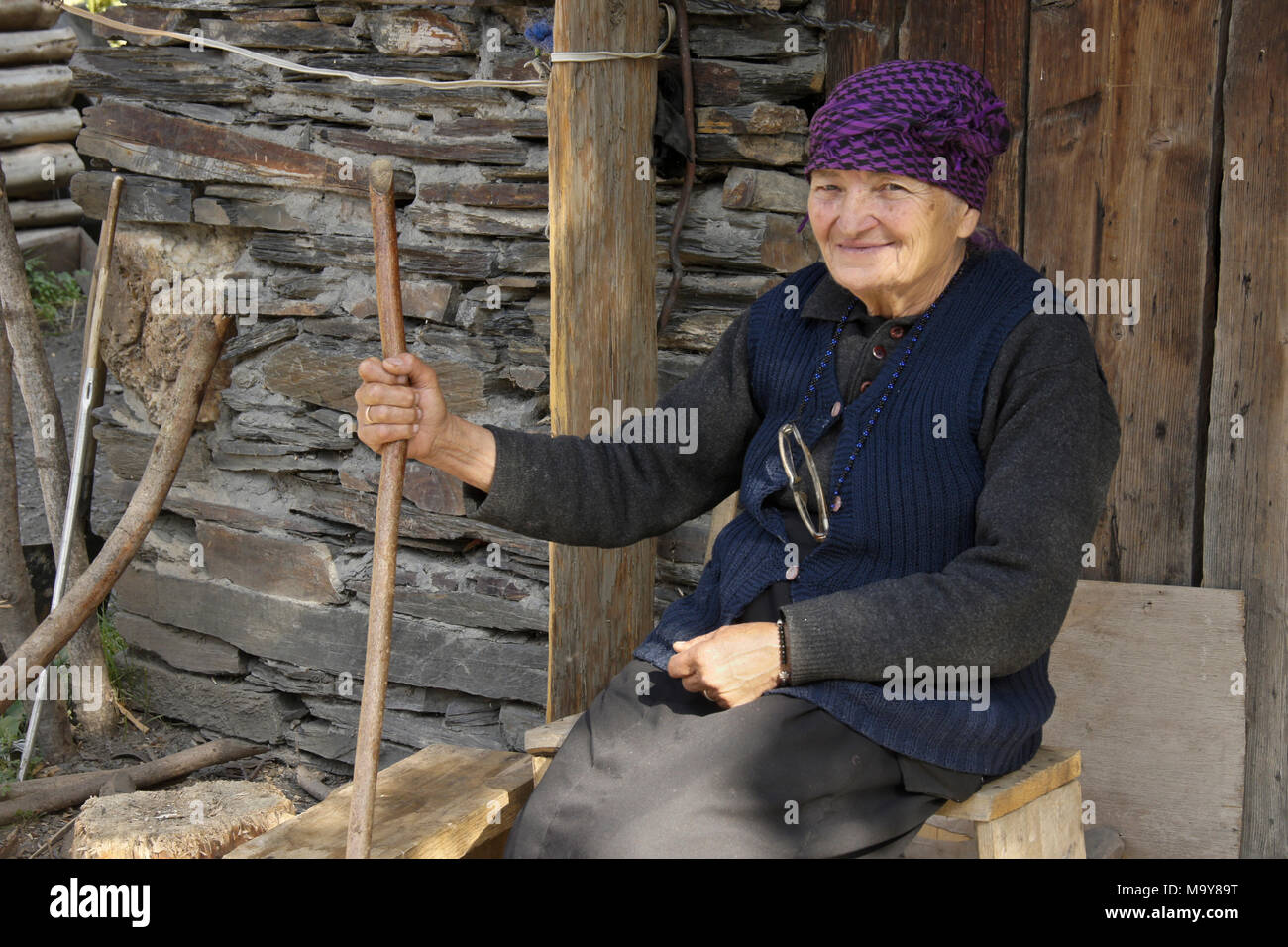 Une femme âgée se trouve à l'extérieur d'un hangar en pierre, Ushguli, Upper Svaneti, Géorgie Banque D'Images
