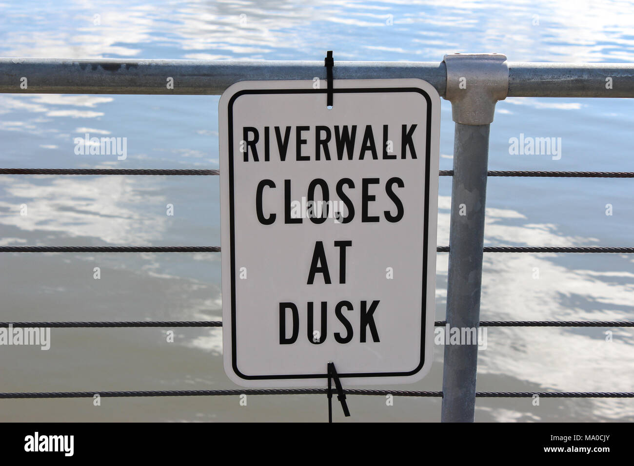 Inscrivez-vous sur un pont en face de l'eau 'Riverwalk se ferme au crépuscule" Banque D'Images