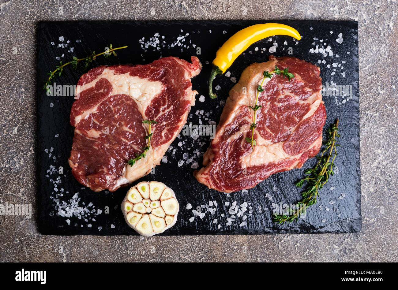 La viande crue. Steak de boeuf sur une planche à découper, de romarin et d'épices, vue du dessus Banque D'Images