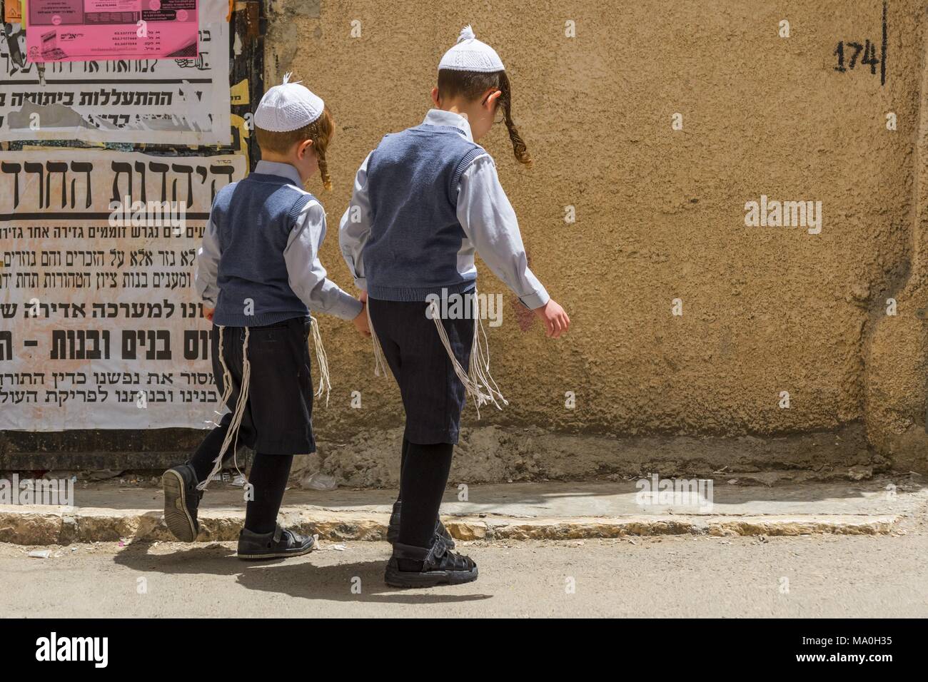 Les garçons juifs ultra orthodoxe en marchant dans la rue à Mea Shearim communauté juive orthodoxe de Jérusalem, Israël trimestre. Banque D'Images