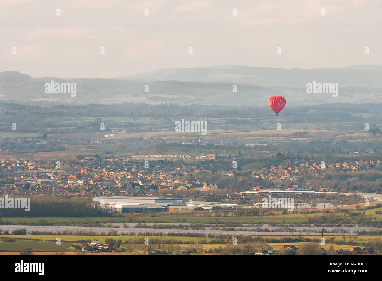 Un seul les red hot air ballon vole flottant au-dessus de maisons d'une petite ville de la campagne environnante. Banque D'Images