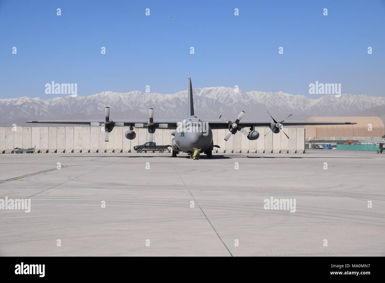 Un Lockheed C-130 Hercules avion assis sur le tarmac de l'aéroport militaire de Kaboul, Afghanistan, en face de la montagne de l'Hindu Kush à l'horizon. Banque D'Images