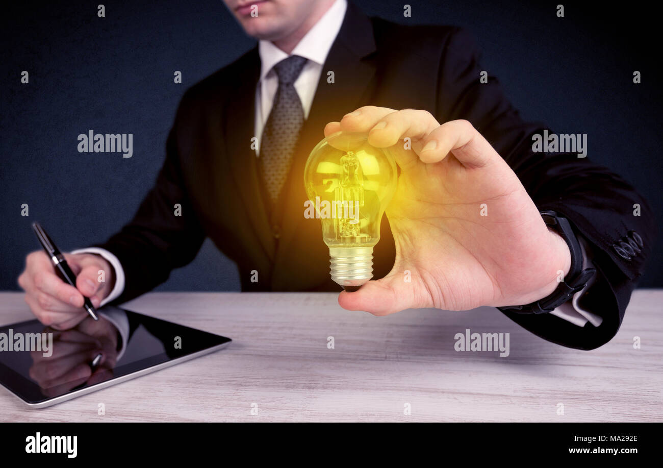 Un business man in suit holding a allumé la lampe jaune dans sa main tout en travaillant au bureau concept. Banque D'Images