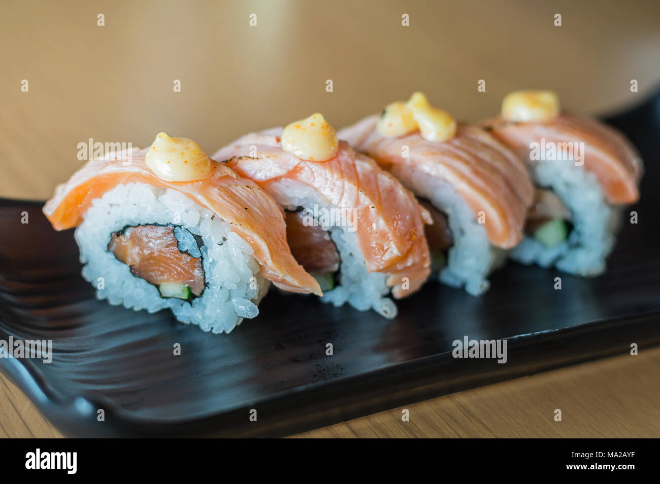 Pavé de saumon sushi roll, nourriture japonaise sur style plat de céramique noire. Banque D'Images