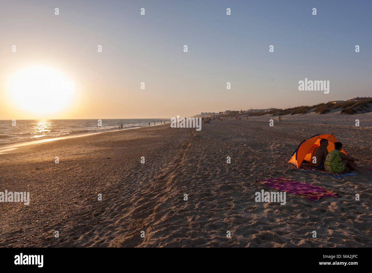 Couple avec un brise-vent de Matalascañas plage au coucher du soleil, d'Almonte, Province de Huelva, Andalousie, espagne. Banque D'Images