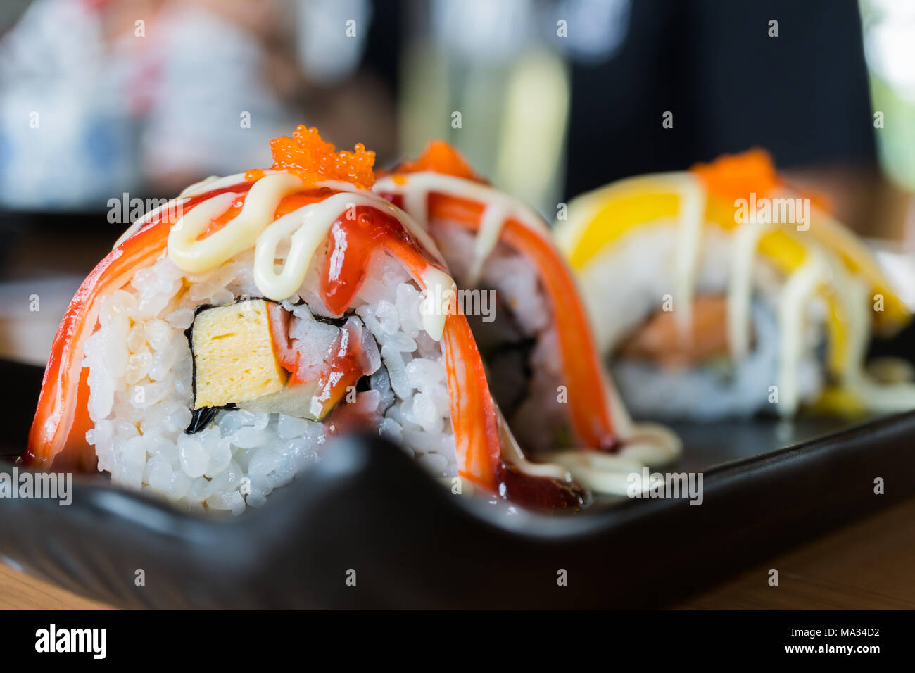 Sushi roll stick de crabe avec sauce aux fraises, nourriture japonaise sur style plat de céramique noire Banque D'Images