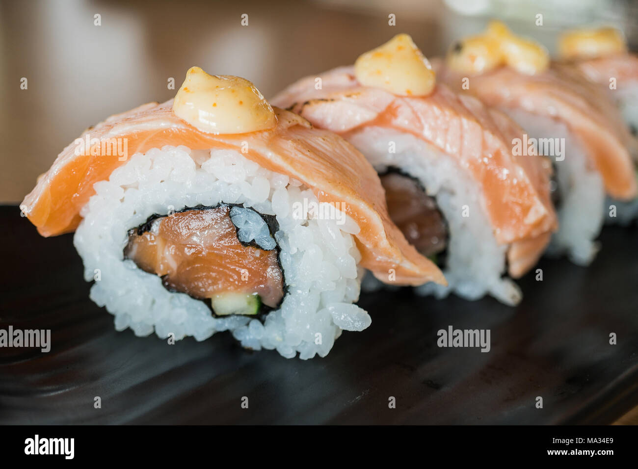 Pavé de saumon sushi roll, nourriture japonaise sur style plat de céramique noire Banque D'Images