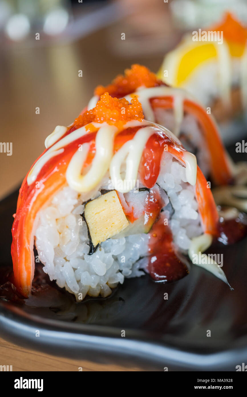 Sushi roll stick de crabe avec sauce aux fraises, nourriture japonaise sur style plat de céramique noire Banque D'Images